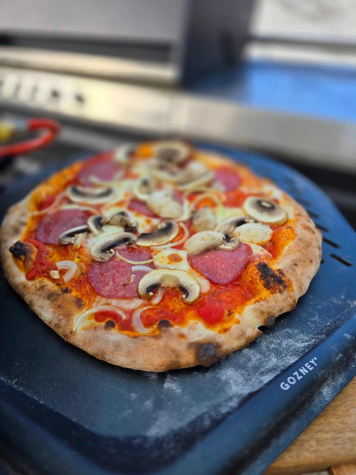 Pizza auf der blauen Gozney-Aluminiumschaufel, kurz vor dem Einschießen